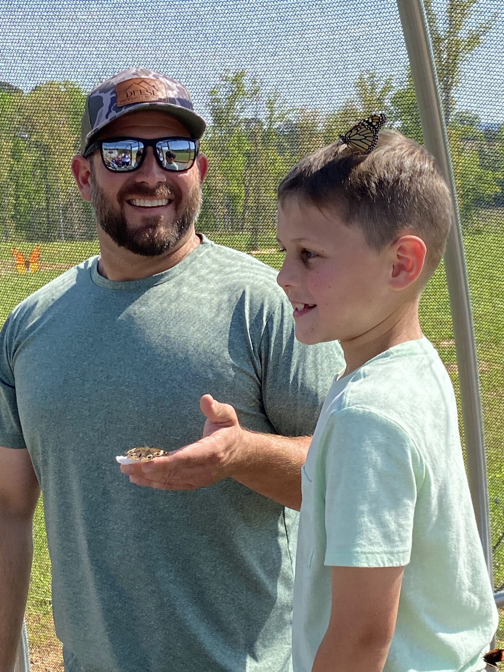 father and son with monarchs landing on them in outdoor flight house
